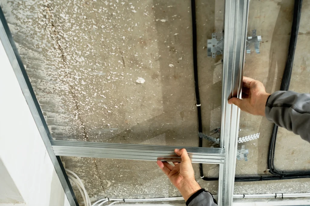 Deux plaquistes professionnels en train de poser et de visser les rails pour fixer ensuite les plaques de placoplâtre pour les cloisons.